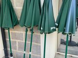 several green umbrellas are lined up against a brick wall