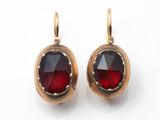 une paire de boucles d'oreilles ornées de grenats rouges sur fond blanc