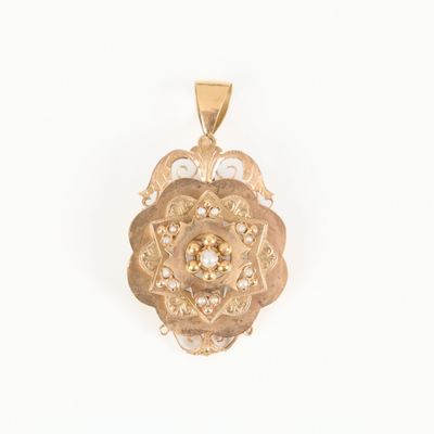 a close up of a gold pendant with a flower design on it