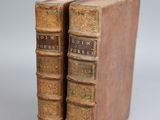two old books sitting on top of each other on a white surface