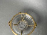 an overhead view of a glass and gold clock on a gray surface