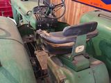 a green tractor parked in a garage with a sign on the wall