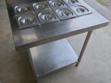 une table en acier inoxydable équipée de six brûleurs
