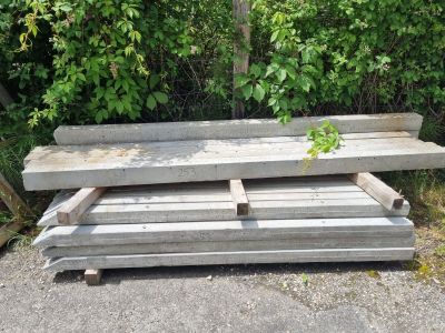 Plusieurs morceaux de bois sont empilés les uns sur les autres devant un buisson