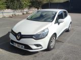 La voiture blanche est garée sur le parking, à côté d'une clôture.