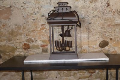 une petite table sur laquelle se trouve une horloge, devant un mur de pierre