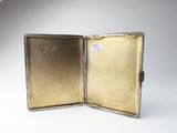 an open silver case with a picture inside of it on a white surface