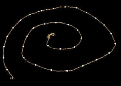 un collier en or avec des perles et une chaîne sur fond noir