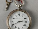 une montre de poche en argent à laquelle est attachée une clé