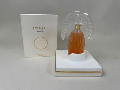 un flacon de parfum posé sur une boîte blanche