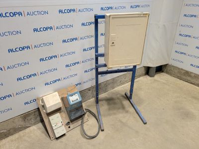 une boîte à laquelle est fixée une autre boîte, devant un mur sur lequel est accrochée une pancarte