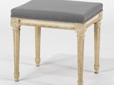 un tabouret blanc avec un coussin gris dessus