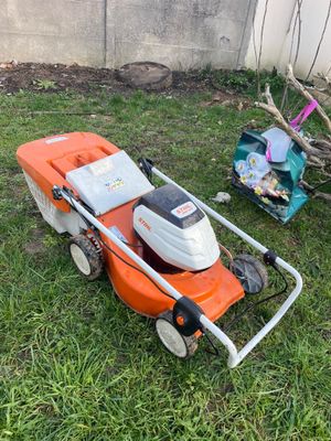 an orange and white lawn mower sitting on top of a lush green field