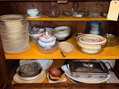 many plates and pans on a shelf in a cabinet