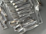 a lot of spoons and forks wrapped in plastic bags