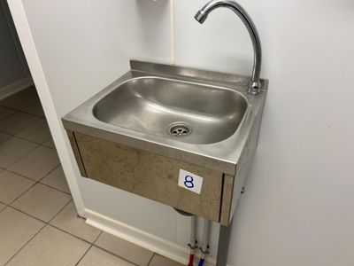 a stainless steel sink with a faucet in the corner of a bathroom