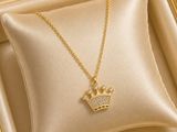 a gold necklace with a crown on it sitting in a gold box