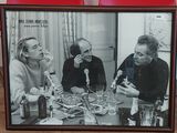 photo encadrée représentant un groupe de personnes assises à une table, un verre à la main