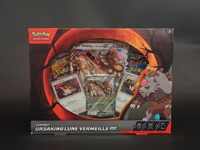 La boîte contient une collection de cartes Pokémon posées sur un fond noir.