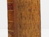 an old book sitting on top of a white table next to a white wall