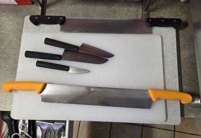 three knives on a cutting board next to a knife sharper