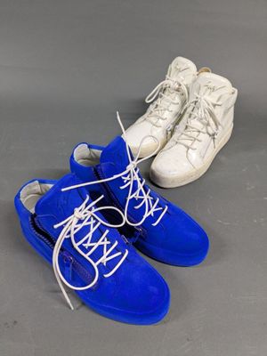 two pairs of blue sneakers with white laces on a gray surface