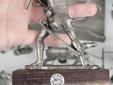 a hand holding a statue of a man with a sword