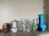 de nombreux vases et verres posés sur une étagère dans une pièce