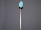 une broche en or et en pierre turquoise montée sur une tige