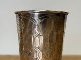 a silver cup on a wooden table with a white wall in the background