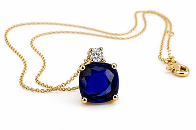 une photo d'un pendentif composé d'un saphir bleu et de diamants, monté sur une chaîne en or