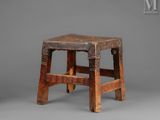 an old wooden stool sitting on top of a gray surface