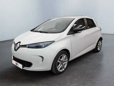 Une voiture blanche est garée dans une pièce au sol noir.