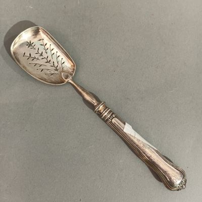 une cuillère ancienne en argent, ornée d'un oiseau, posée sur une table