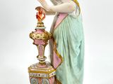 a figurine of a woman standing next to a vase