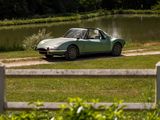 a green car parked on the side of the road by the water
