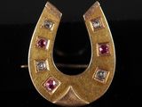 a close up of a gold horseshoe shaped ring with pink and white stones