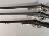 five old guns mounted on a wall in a room