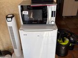 un petit réfrigérateur et un micro-ondes posés sur un sol carrelé