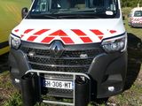 une camionnette blanche ornée d'une bande rouge et blanche, garée dans l'herbe