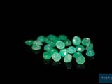 a close up of a bunch of green emeralds on a black surface