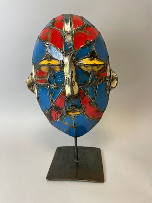 un gros plan d'un masque bleu et rouge posé sur un support métallique