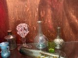 une étagère en verre sur laquelle sont posées des bouteilles et des vases en verre