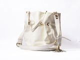 cream leather bucket bag with tassels on white background
