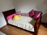 a bed with pillows and a lamp on it in the corner of a room