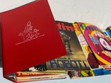 a red book with a red cover sitting on top of a pile of magazines