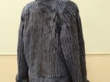 grey fur jacket on a mannequin stand in front of a white wall