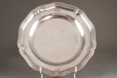 un plat ancien en argent posé sur un socle, sur fond gris