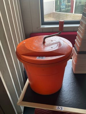 un grand seau orange posé sur une étagère près d'une fenêtre