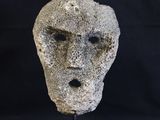 une image représentant un visage sculpté dans la pierre sur fond noir